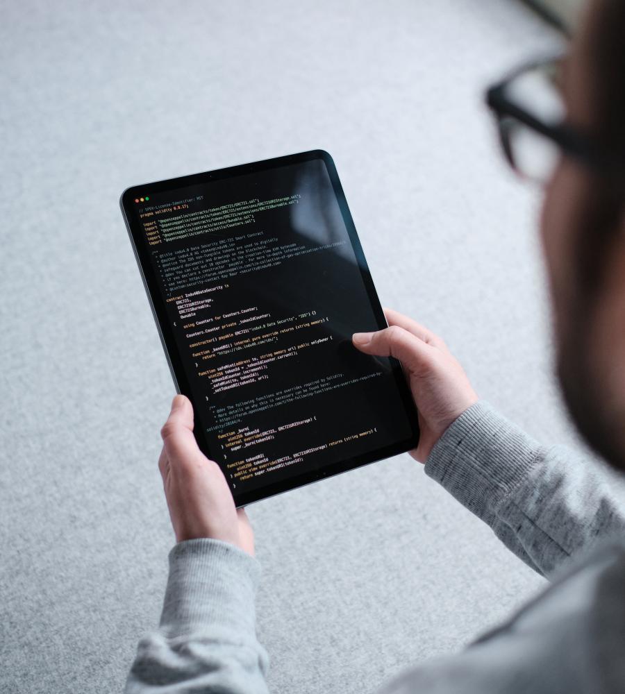 Person holds iPad in hands on which part of a smart contract is displayed